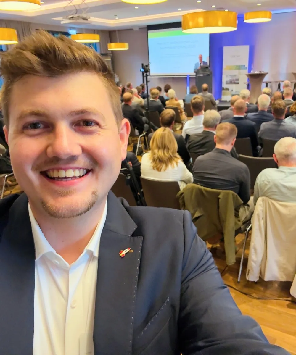 Justus Kornath auf einer Konferenz, die er organisiert hat, hinter ihm Publikum und Bühne